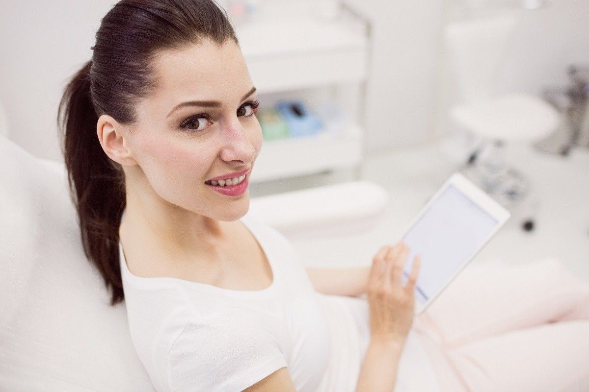 Woman smiling during a comfortable dental visit while reviewing same-day CEREC treatment options